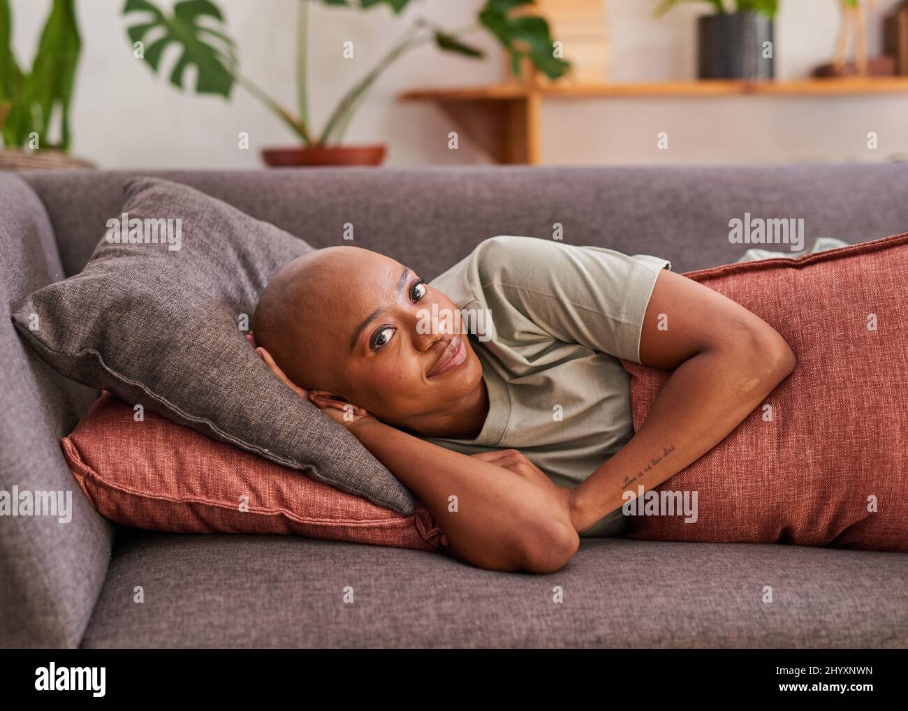 Une jeune femme repose sur le canapé et sourit à la caméra Banque D'Images