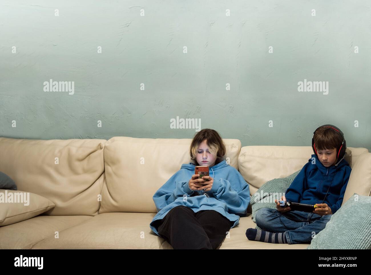 Deux enfants jouant avec des gadgets sur le canapé à la maison Banque D'Images