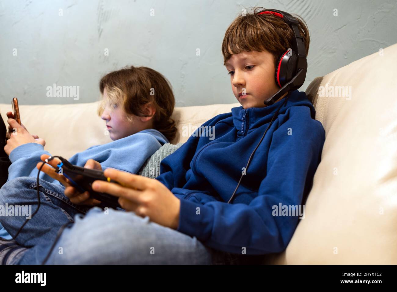 Deux enfants jouant avec des gadgets sur le canapé à la maison Banque D'Images