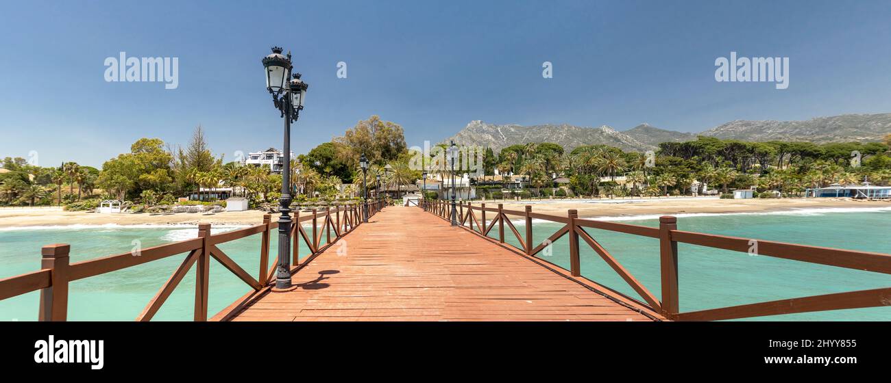 Vue sur le pont en bois rouge Embarcadero à Marbella. Vue sur la zone de luxe Puente Romano, les urbanisations chères. Montagne 'la Concha'. Banque D'Images