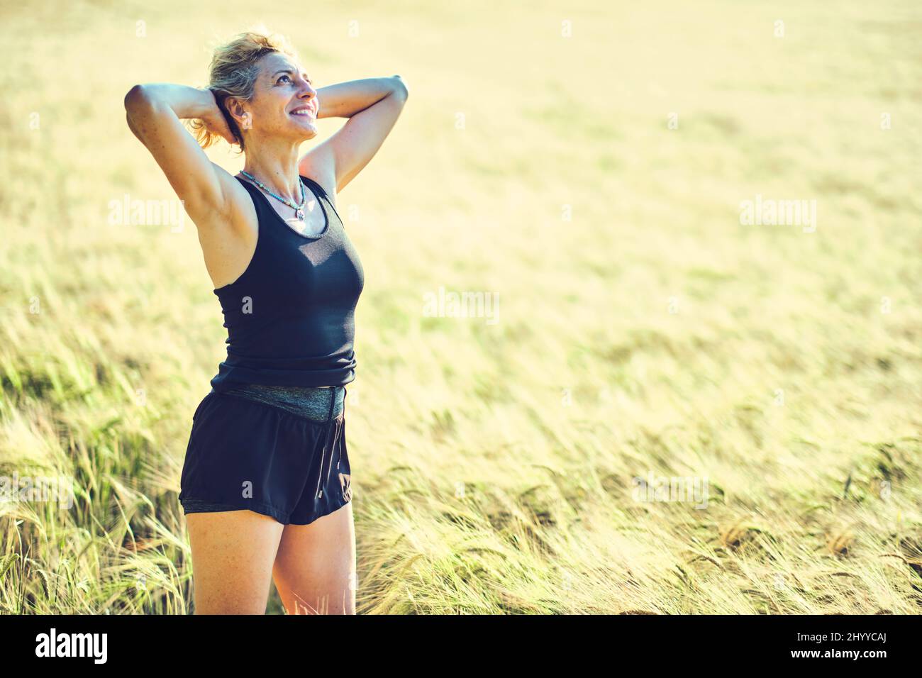Portrait d'une jeune femme de race blanche mature dans des vêtements de sport en plein air dans un paysage de terres céréalières. Concept de style de vie. Banque D'Images