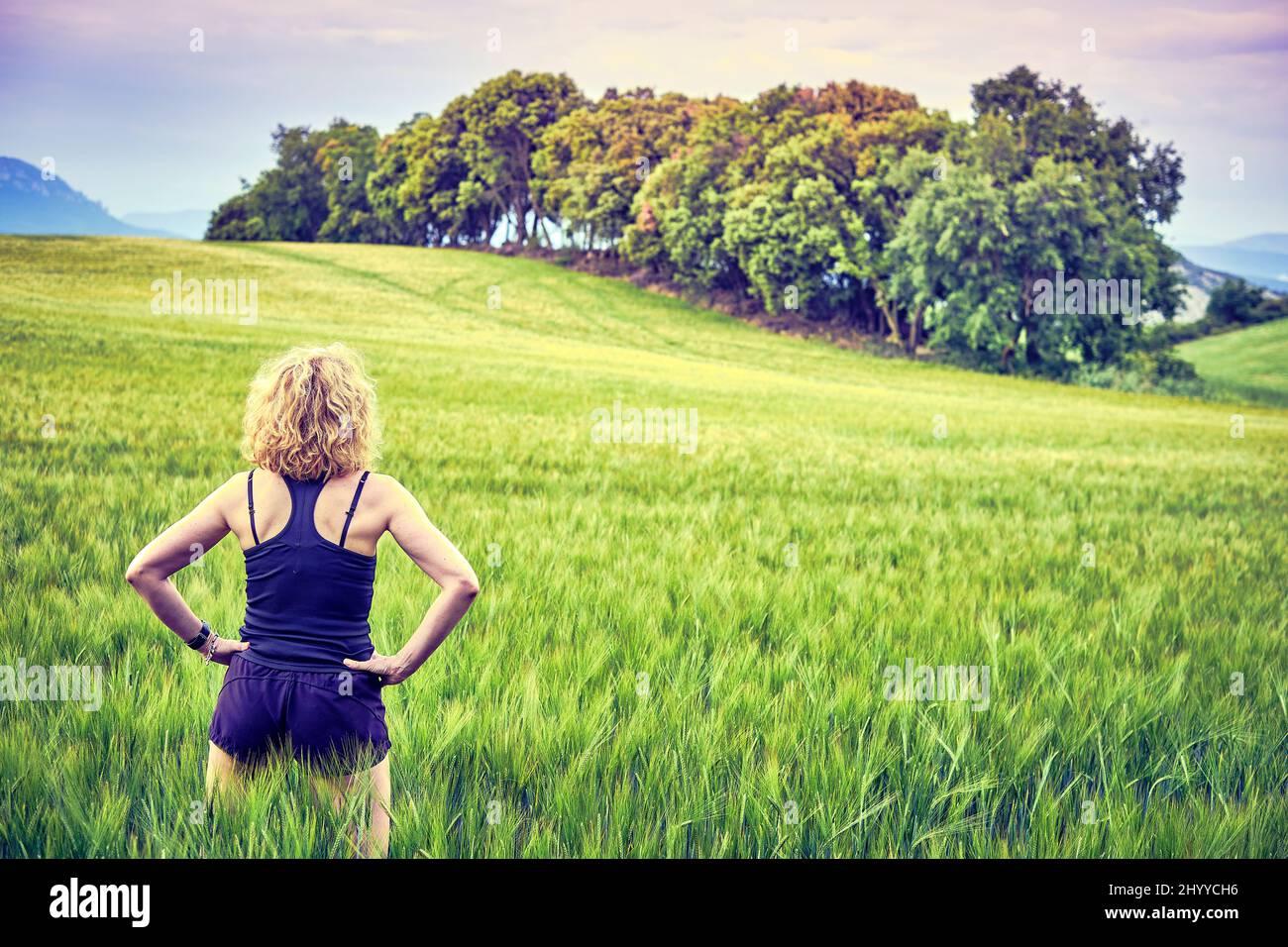 Portrait arrière d'une jeune femme caucasienne adulte avec des cheveux blonds dans des vêtements de sport en plein air dans un paysage de céréales agricoles. Navarre, Espagne, Europe. Banque D'Images