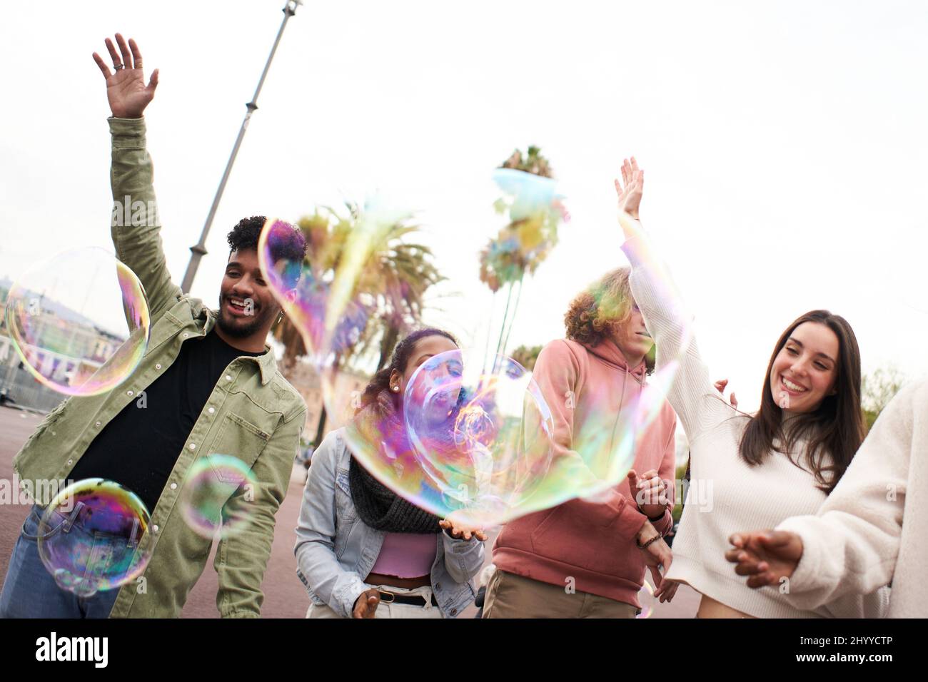 Bonne fête avec une bulle de savon. Les jeunes adultes dansent en plein air. Groupe d'amis qui s'amusent Banque D'Images