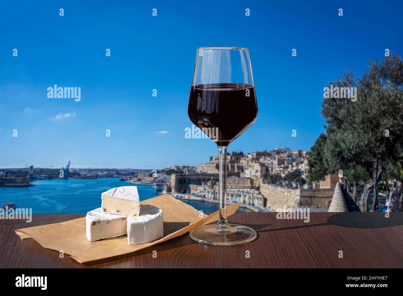 Verre de vin rouge au fromage avec vue sur le mur de la ville et le port de la Valette, Malte. Banque D'Images