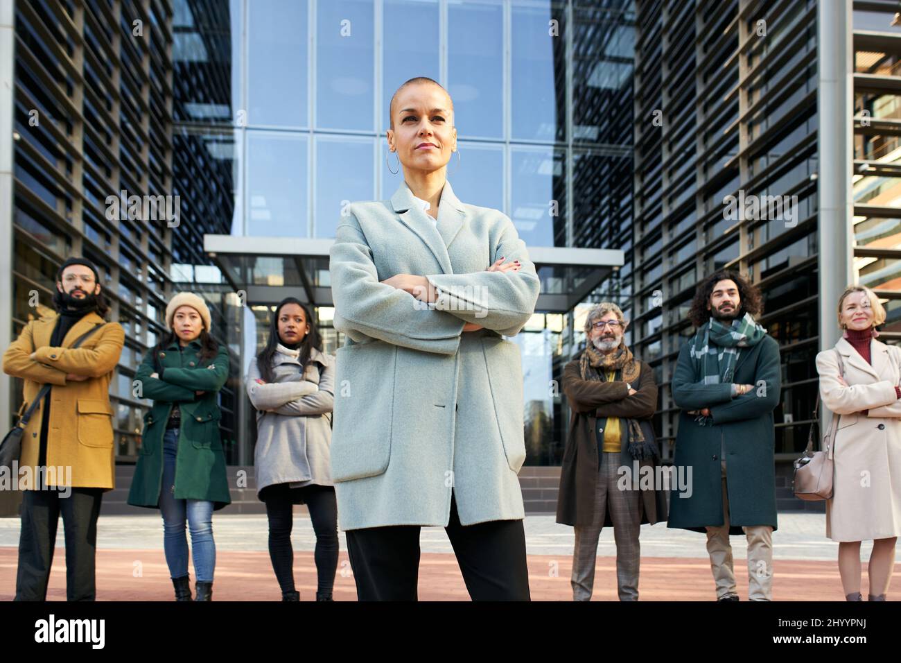 La directrice de l'entreprise pose avec son équipe devant le bâtiment de l'entreprise. Les gens d'affaires suivent le leader de la réussite et les femmes Banque D'Images