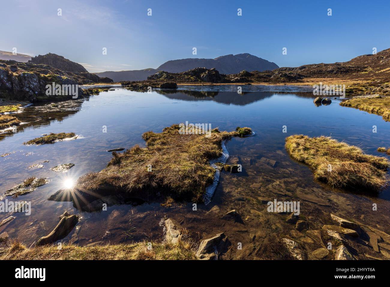 Un Innominent Tarn partiellement gelé en hiver dans les Buttermere Fells, Lake District, Angleterre Banque D'Images