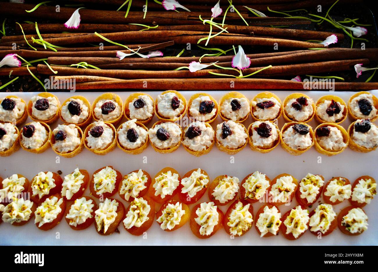 Coupes de canapés avec salade de poulet et abricots secs au fromage Boursin pour une soirée cocktail sur un plateau décoré de bâtonnets de cannelle et de pétales de fleurs. Banque D'Images Coupes de canapés avec salade de poulet et abricots secs au fromage Boursin pour une soirée cocktail sur un plateau décoré de bâtonnets de cannelle et de pétales de fleurs. Banque D'Images