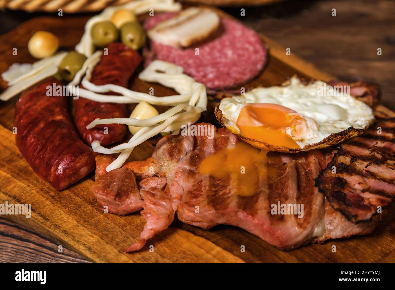 Différentes sortes de saucisses grillées avec des œufs. Une sélection de viandes gastronomiques grillées sur une planche de bois rustique. Saucisses grillées avec du pain maison. Banque D'Images