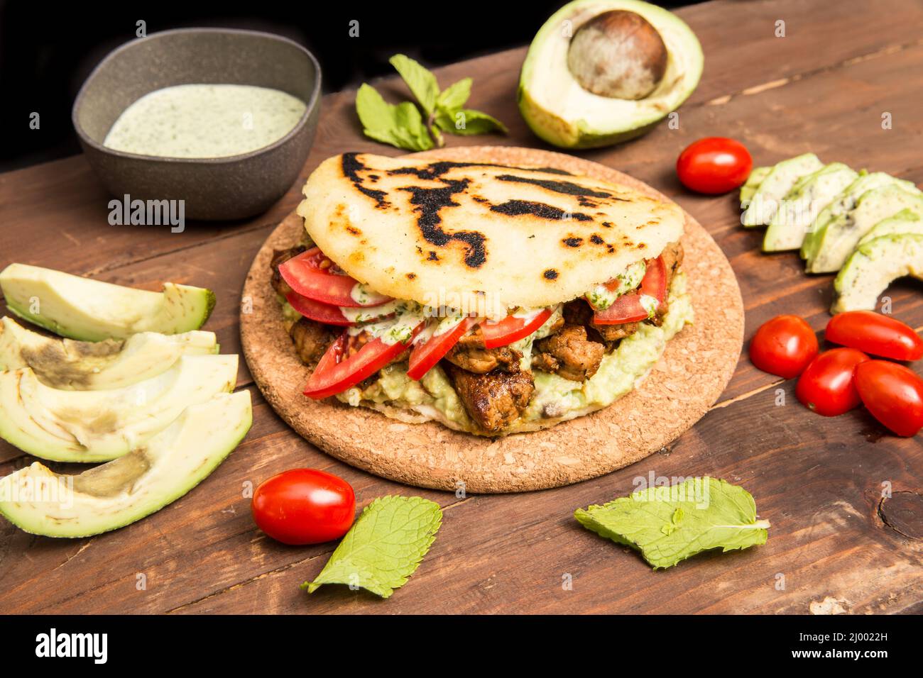 Arepas - cuisine colombienne traditionnelle originaire d'Amérique latine, sur une table en bois rustique, mélangée à de la viande, des légumes et de l'avocat Banque D'Images