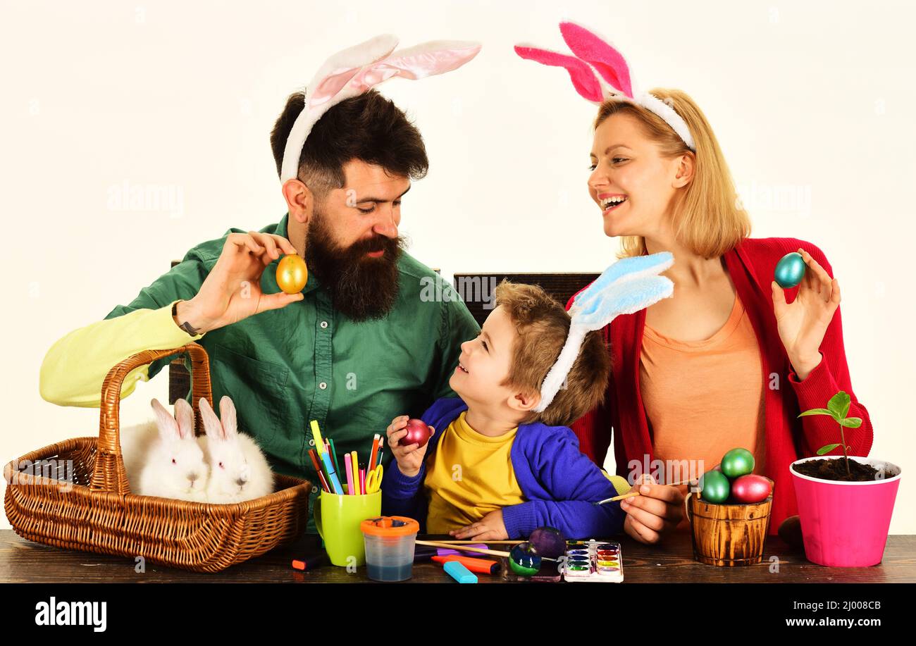 Une famille heureuse s'assoit à une table en bois avec des œufs de Pâques. Famille dans les oreilles de lapin se préparant pour les vacances. Banque D'Images