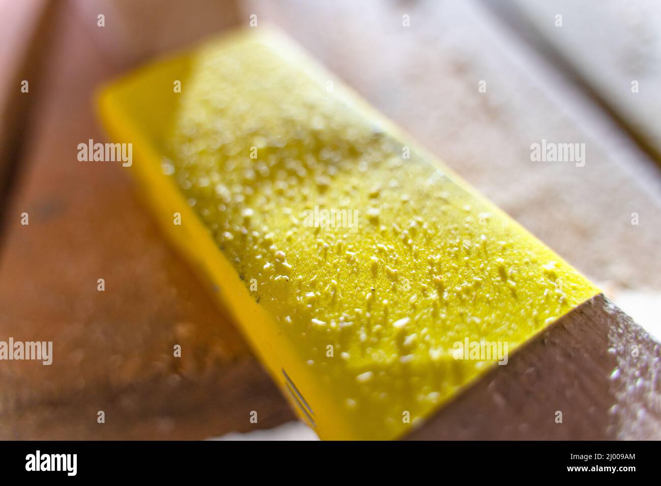 Papier de verre jaune de gros plan à fraction fine. Papier abrasif sur un bloc de bois Banque D'Images