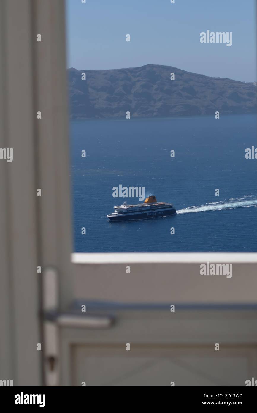 Santorini, Grèce - 10 mai 2021 : vue à travers une fenêtre et un ferry approchant le port de Santorini Banque D'Images