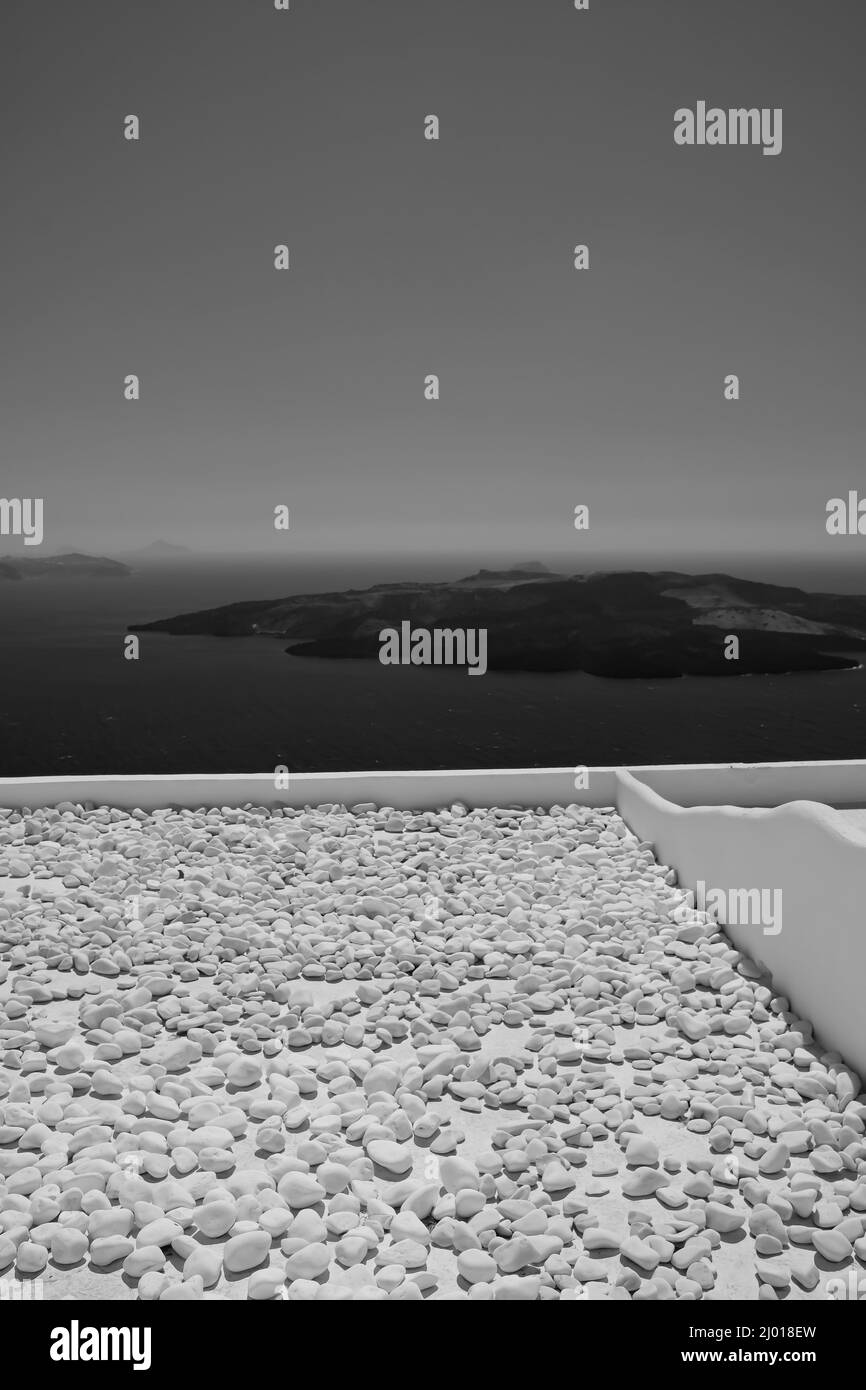 Vue sur le volcan de Santorin depuis un toit rempli de pierres en noir et blanc Banque D'Images