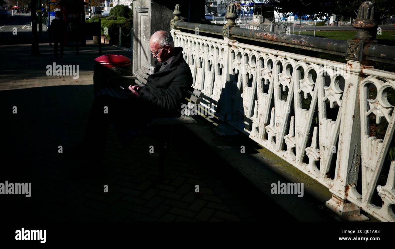 Un vieil homme assis sur une chaise dans un parc de Queens, en Nouvelle-Zélande Banque D'Images