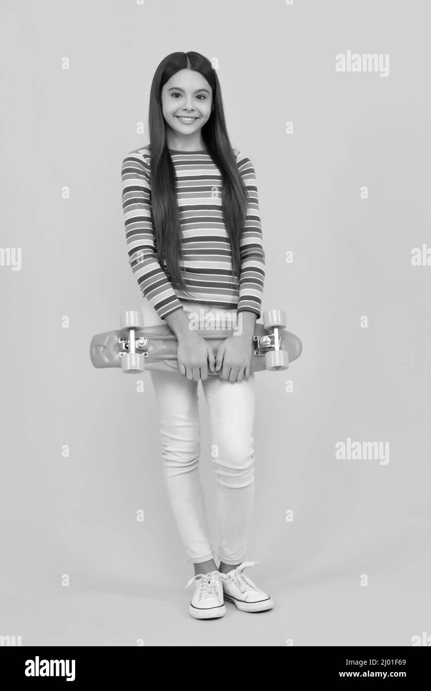 planche à roulettes. enfant gai tenant un panneau de penny. jeune fille sur fond jaune. Banque D'Images