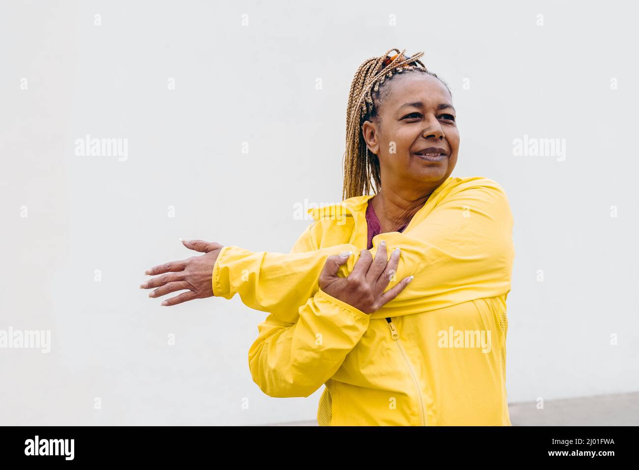 Femme africaine senior faisant la routine d'entraînement tout en s'étirant à l'extérieur - Focus sur le visage Banque D'Images