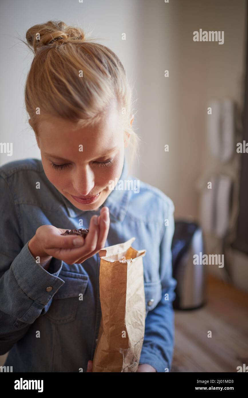 Arôme frais de grains de café. Une jeune femme sentant des grains de café frais dans sa cuisine. Banque D'Images