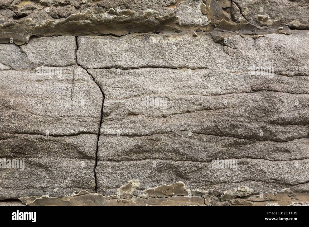 Gros plan des fissures dans le mur de fondation en pierre de granit gris. Banque D'Images