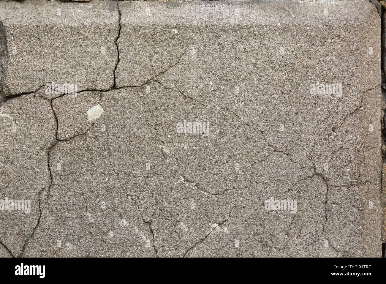 Gros plan des fissures dans le mur de fondation en pierre de granit gris. Banque D'Images