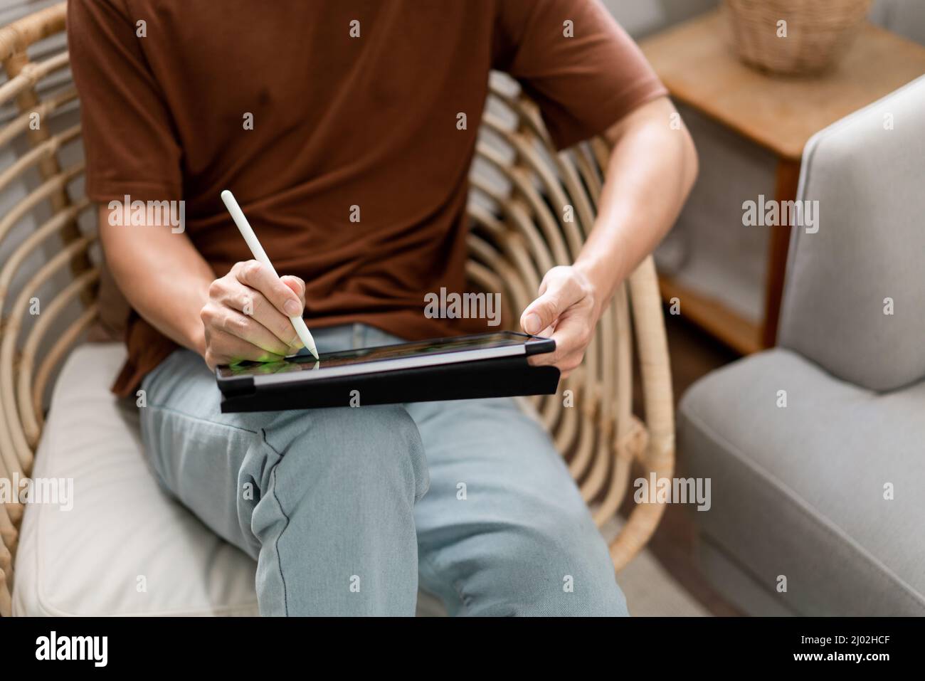 Concept de technologie le jeune homme qui est assis sur la chaise tenant son iPad et notant quelque chose sur lui. Banque D'Images
