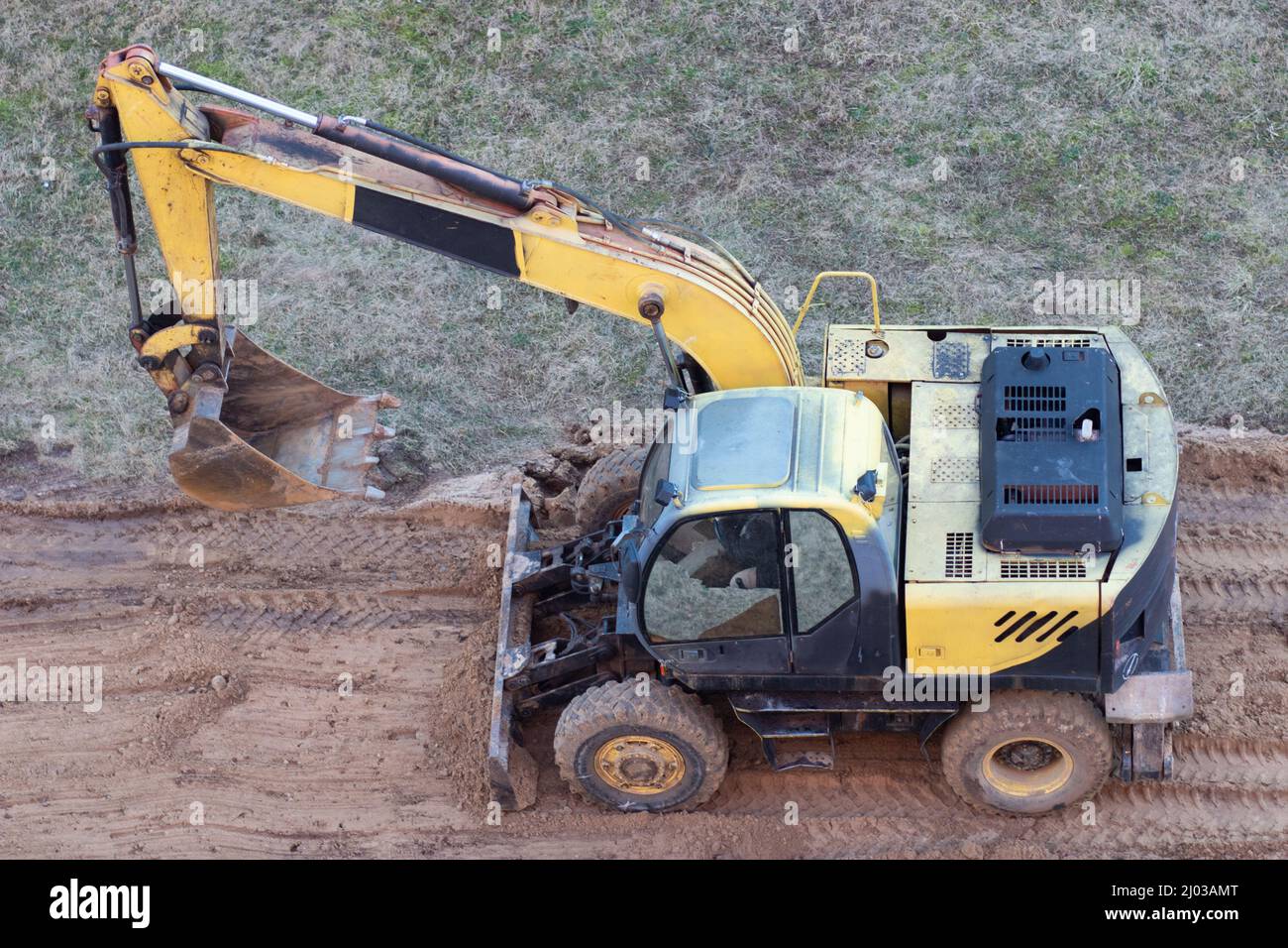 Une chargeuse sur pneus creuse le sol sur un chantier de construction pour paver une route Banque D'Images