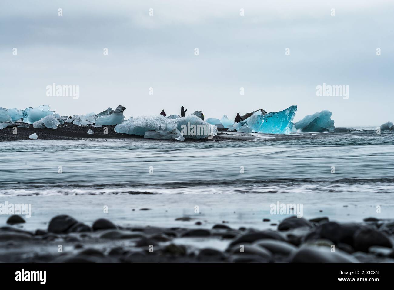 Des icebergs bleus sur la plage de sable noir avec des touristes Banque D'Images