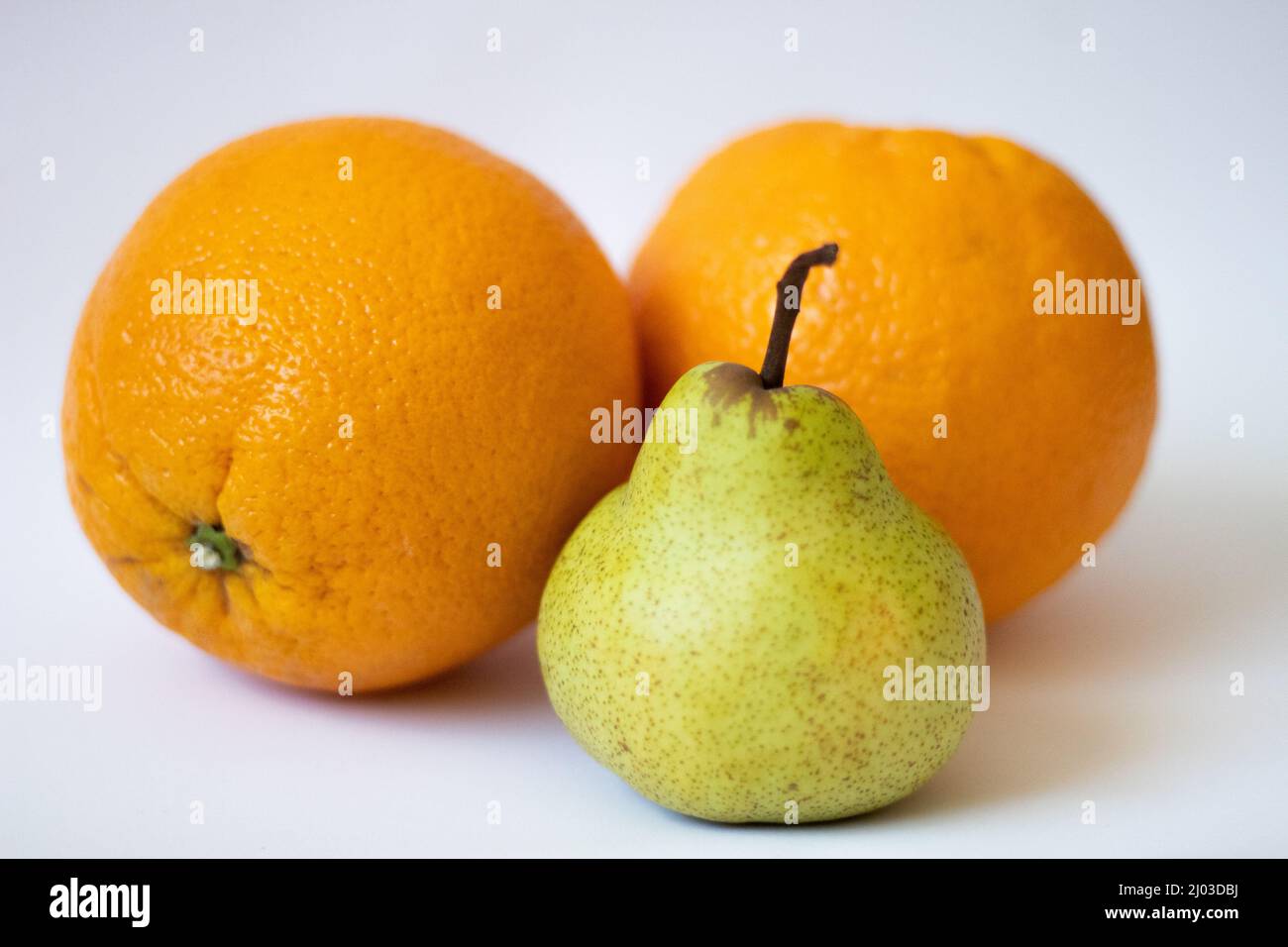 Une poire et deux oranges sur fond blanc isolé Banque D'Images