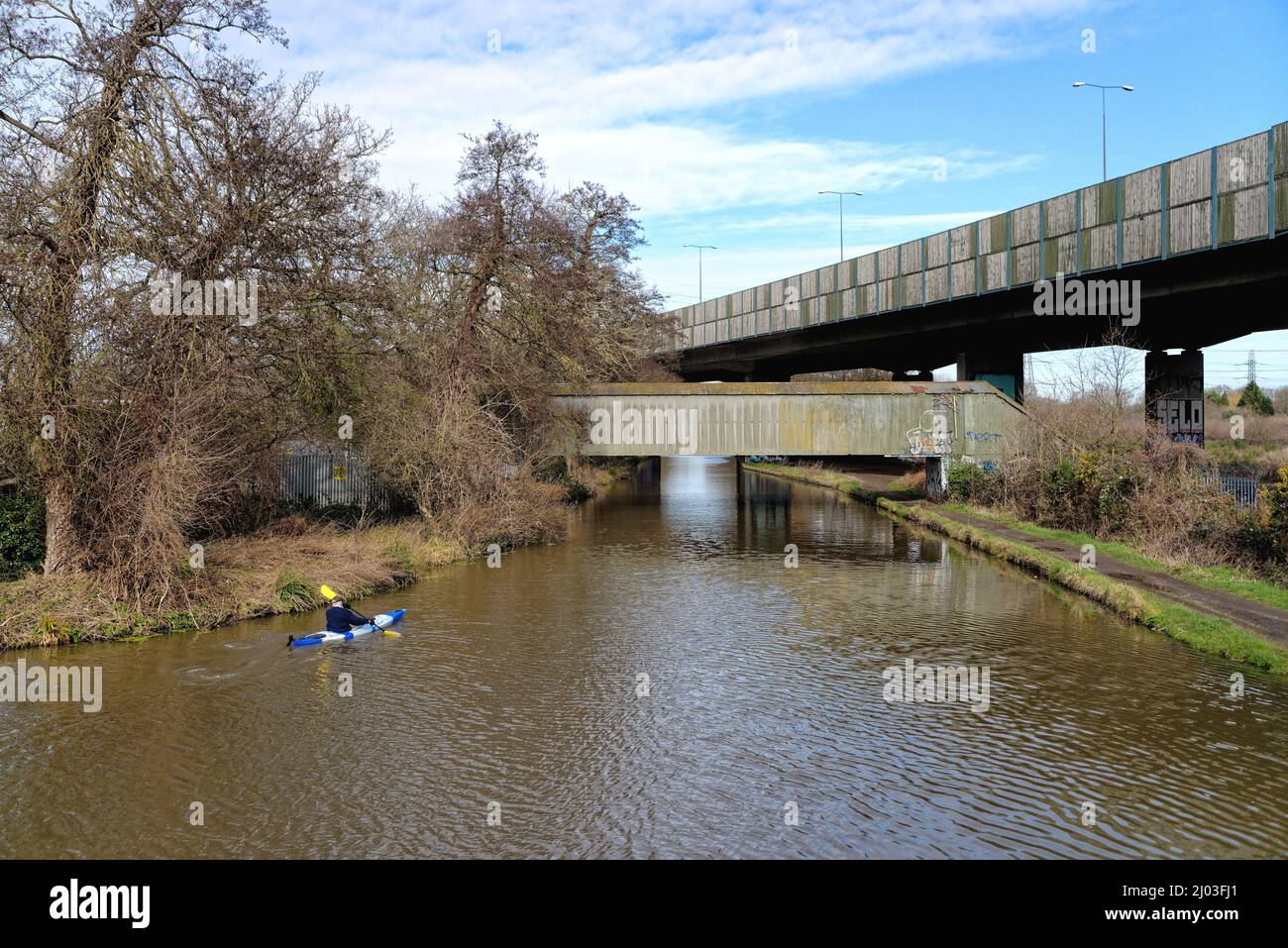 Un seul kayakiste passant sous le pont autoroutier surélevé de M25 qui traverse le canal de navigation de River Wey à New Haw Surrey, Angleterre, Royaume-Uni Banque D'Images