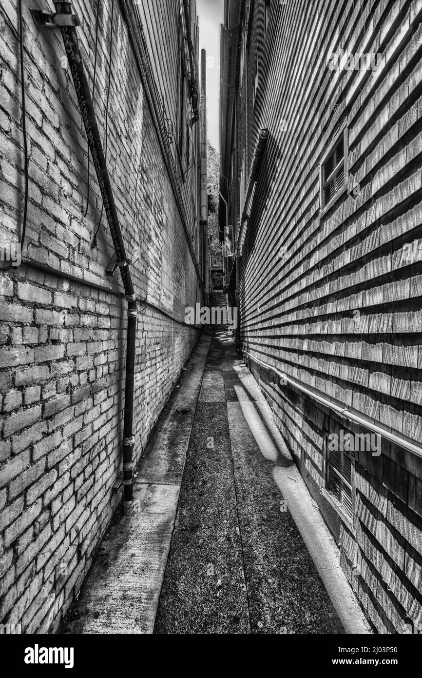 Photo en noir et blanc d'une rue étroite avec des murs de briques Banque D'Images