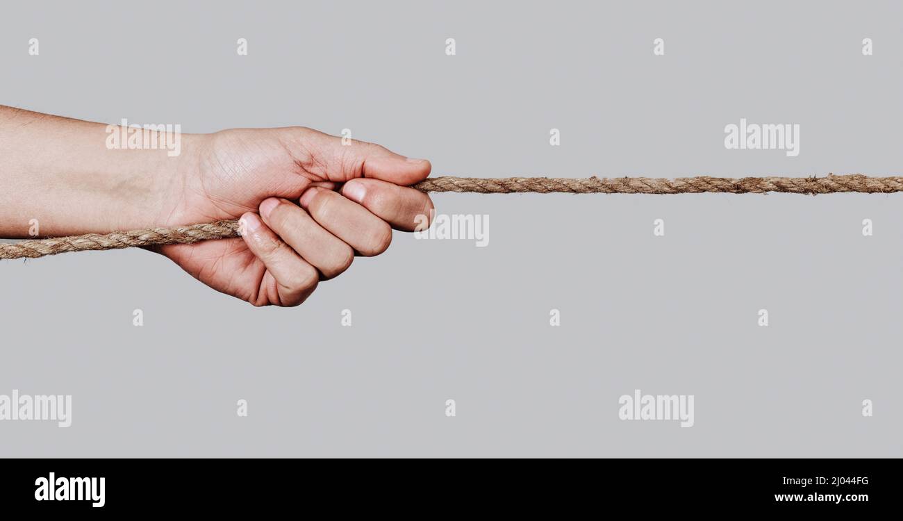 gros plan d'un homme caucasien tirant une corde contre un fond gris pâle, dans un format panoramique à utiliser comme bannière web ou en-tête Banque D'Images