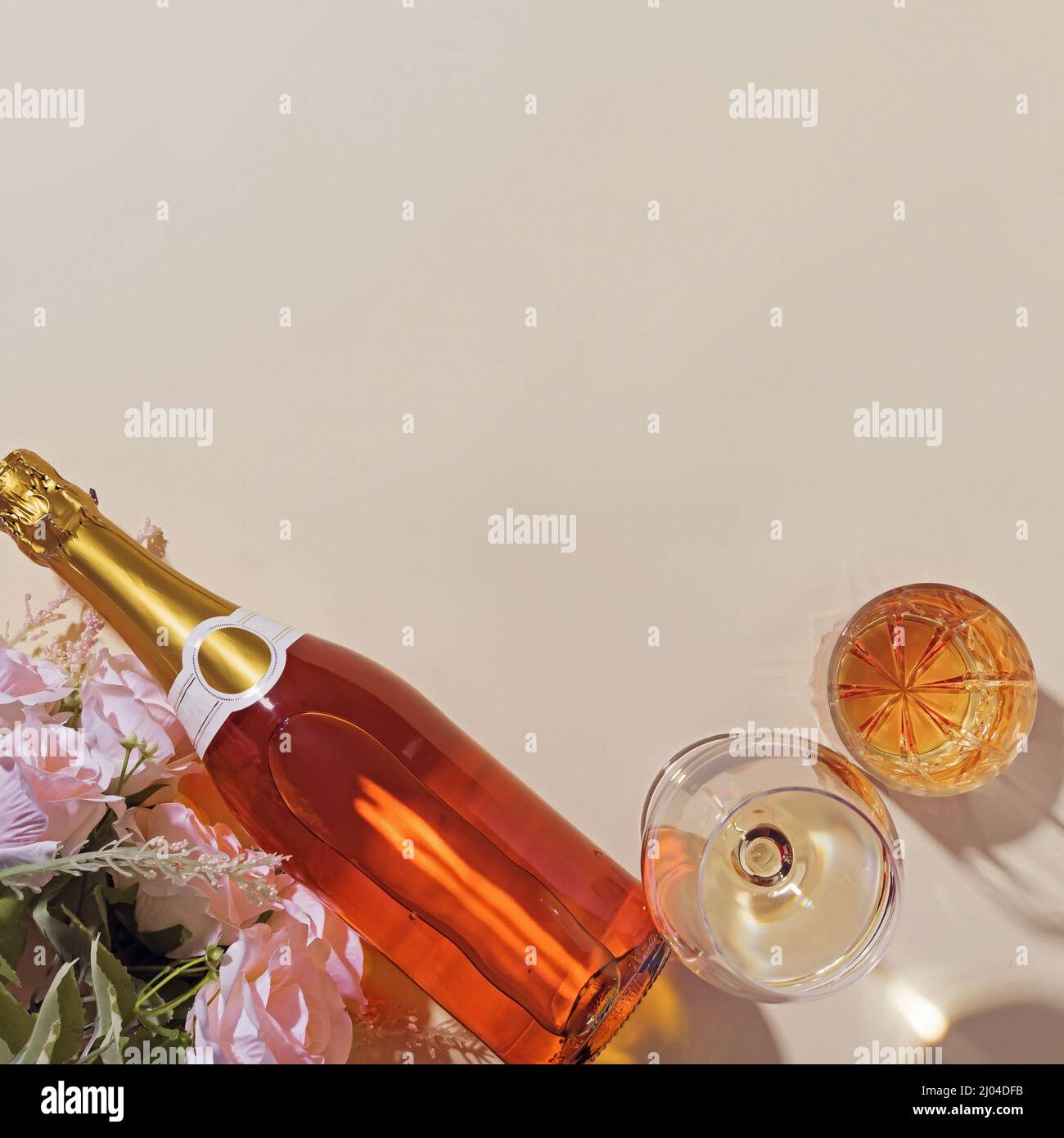 Arrangement festif avec des fleurs et une bouteille de champagne à côté de plein deux verres remplis de boisson alcoolisée comme carte d'anniversaire ou d'anniversaire avec c Banque D'Images