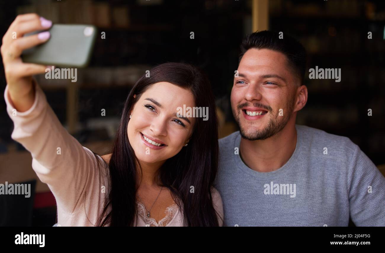 Le temps de selfie avec ma personne préférée. Photo courte d'un jeune couple qui prend un selfie tout en étant assis ensemble. Banque D'Images