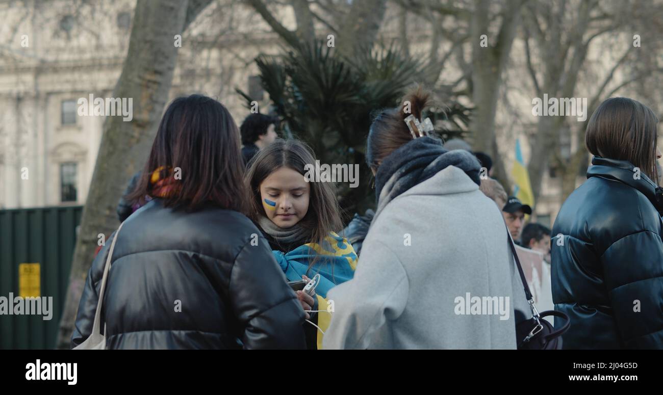 Londres, Royaume-Uni - 03 06 2022 : une jeune femme ukrainienne protestait sur la place du Parlement, avec des rayures bleues et jaunes peintes sur sa joue. Banque D'Images