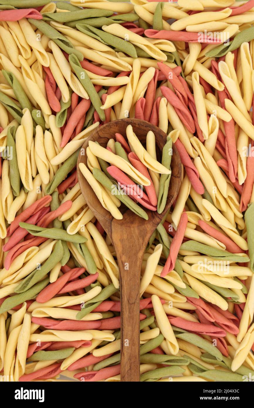 Fusilli pulgiesi pâtes tricolores dans une cuillère en bois d'olive et formant un fond abstrait. Concept alimentaire italien sain et glucidique. Banque D'Images