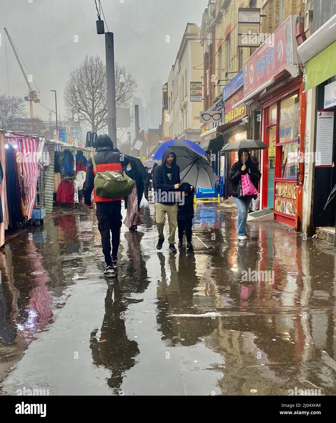 Whitechapel, Tower Hamlets, est de Londres, Royaume-Uni. 16th mars 2022. Météo au Royaume-Uni : les citoyens se sont empaouis par la pluie torrentielle, transportant de la poussière saharienne. La poussière a été ramassée par Storm Celia et déplacée vers l'intérieur à travers le Royaume-Uni après avoir tourné le ciel orange en Espagne. Crédit : Laura Downs/Alay Live News Banque D'Images