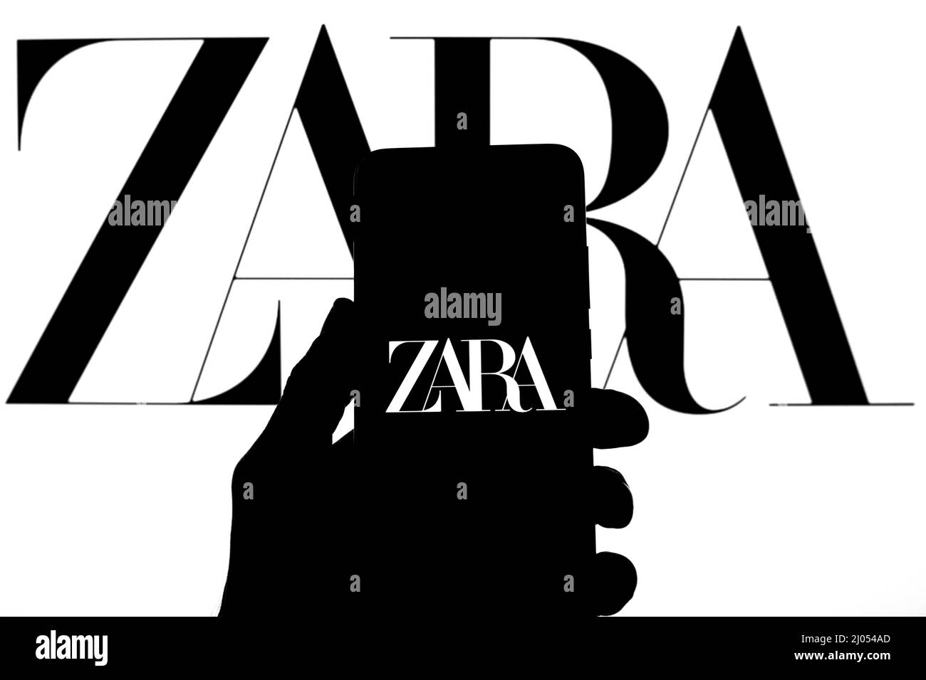 Sur cette photo, un logo Zara apparaît sur un smartphone avec un logo Zara en arrière-plan. Banque D'Images