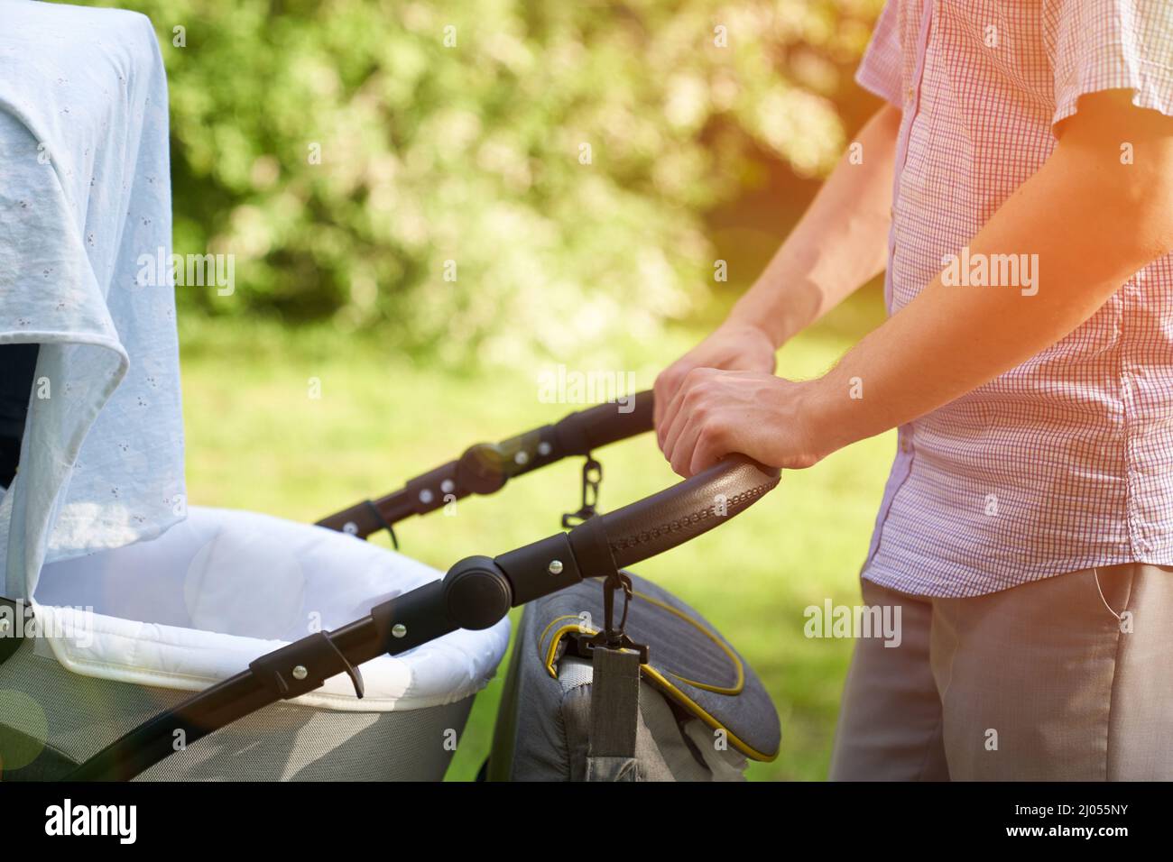 Un jeune père marchant dans le parc avec un bébé dans une poussette. Gros plan des mains des hommes avec une poussette. Concept de fête des pères. Photo de haute qualité Banque D'Images