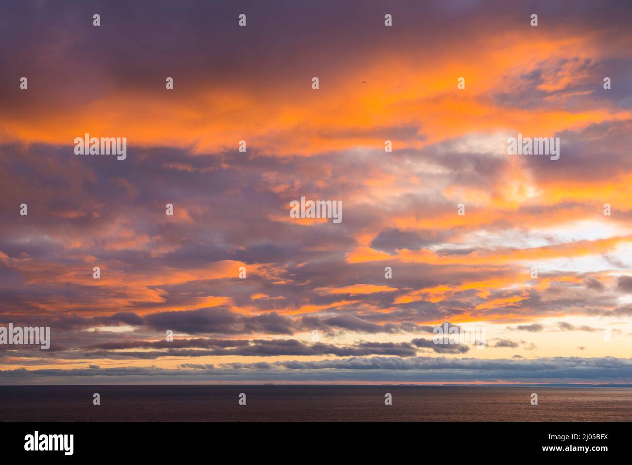 West Bay Dorset, Royaume-Uni. 16th mars 2022. Météo Royaume-Uni. Un coucher de soleil spectaculaire vu depuis le South West Coast Path à West Bay à Dorset, les nuages s'allument en orange alors que le ciel doit se dégager après une journée de pluie intense. Crédit photo : Graham Hunt/Alamy Live News Banque D'Images