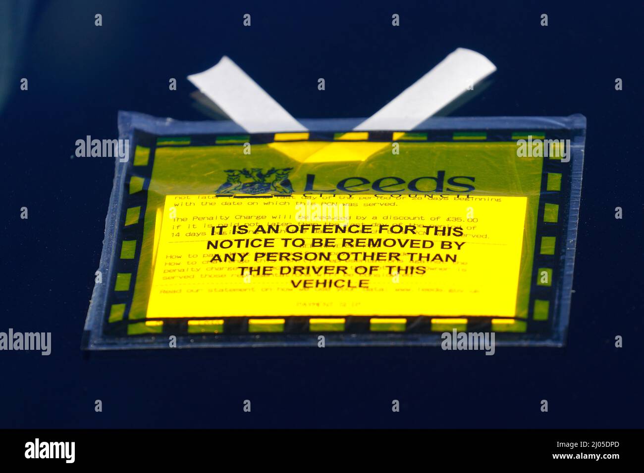 Un gros plan d'une amende de stationnement par le conseil municipal de Leeds sur un pare-brise de voiture pour le stationnement sur une seule ligne jaune Banque D'Images