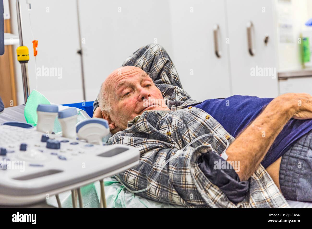 Senior malade couché dans un lit d'hôpital avec perfusion iv attaché à sa main Banque D'Images