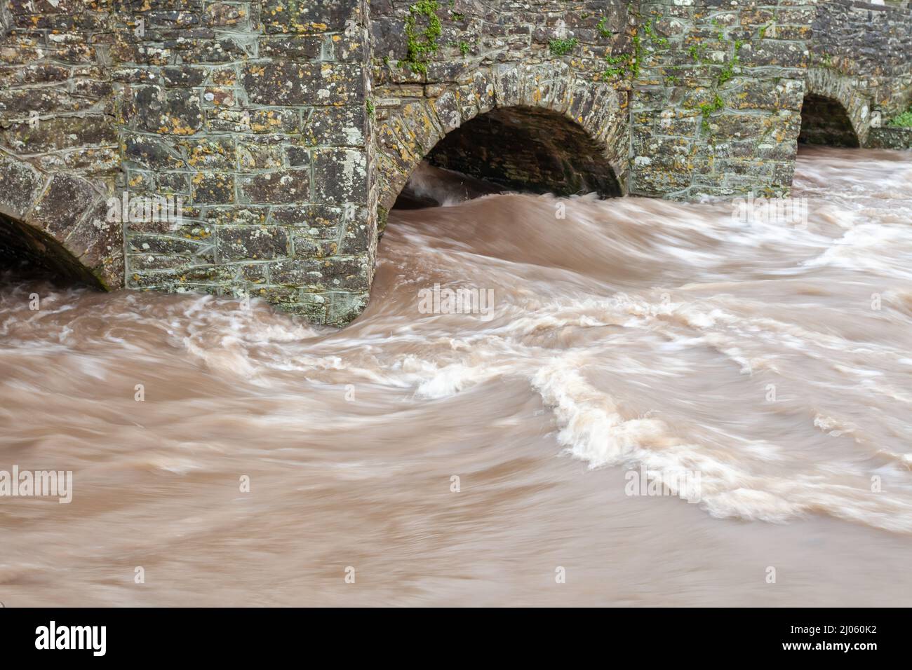 Rivière à écoulement rapide inondation eau qui se précipitent à travers les arches de l'ancien pont en pierre Banque D'Images