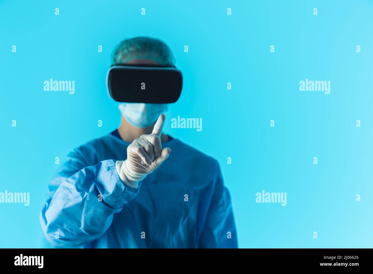 Médecin professionnel portant des lunettes de réalité virtuelle se concentre sur le doigt de premier plan, studio isolé tourné avec fond bleu. Photo de haute qualité Banque D'Images