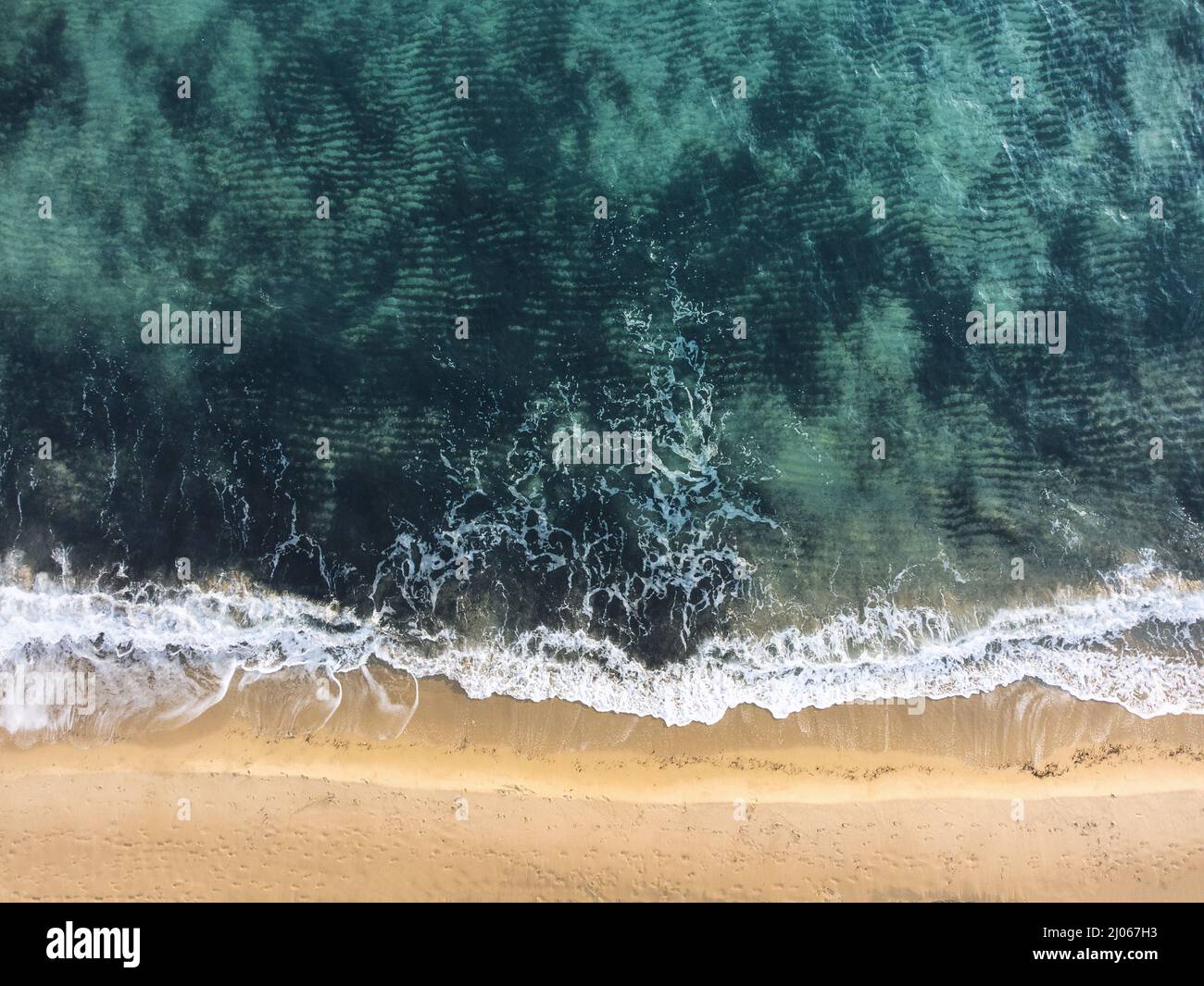 Vue aérienne d'une plage avec une mer bleue et du sable jaune. Banque D'Images