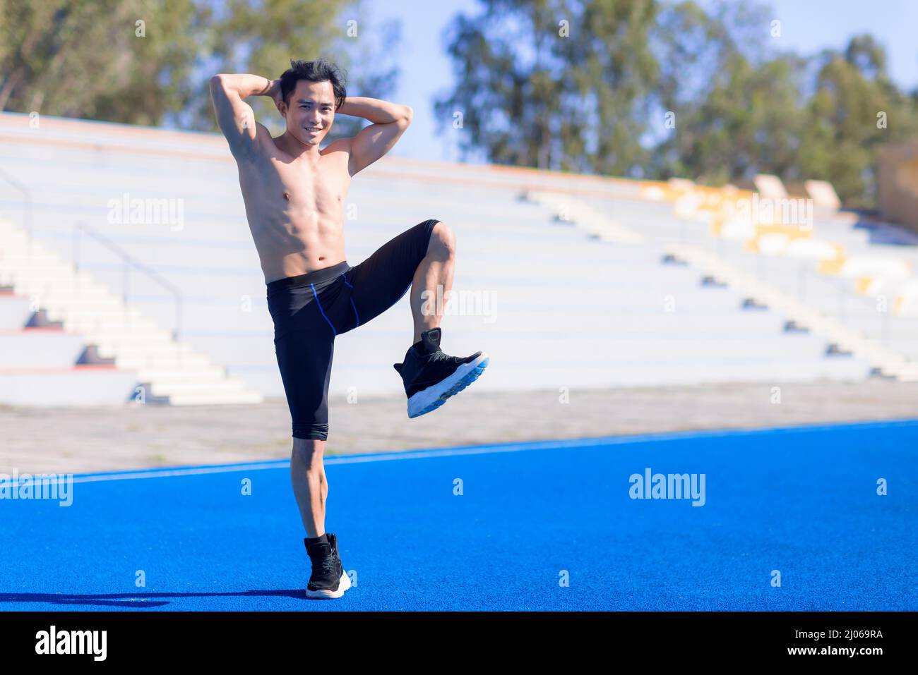 Jeune homme en forme avec des muscles étirant et se réchauffant avant l'entraînement à l'extérieur Banque D'Images