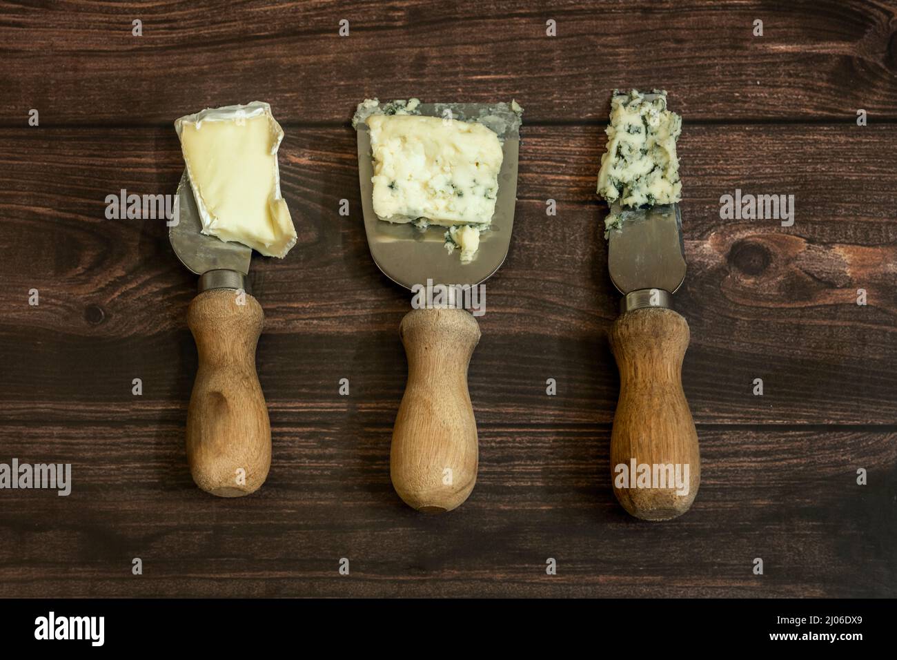 Trois couteaux de fromage bleu et brie sur table en bois Banque D'Images