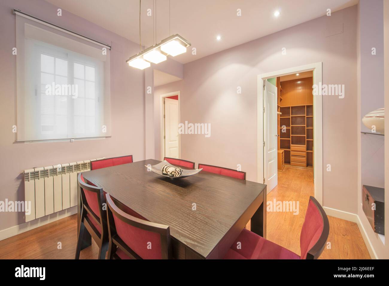 chambre avec table à manger en bois sombre et chaises rembourrées en velours rouge aux murs peints en violet Banque D'Images