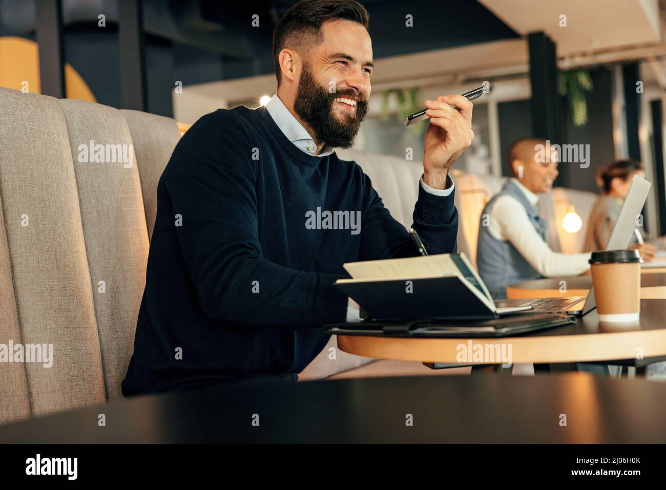 Homme d'affaires joyeux prenant des notes pendant un appel téléphonique. Un jeune homme d'affaires souriant en faisant des plans avec ses associés par téléphone. Moderne Banque D'Images