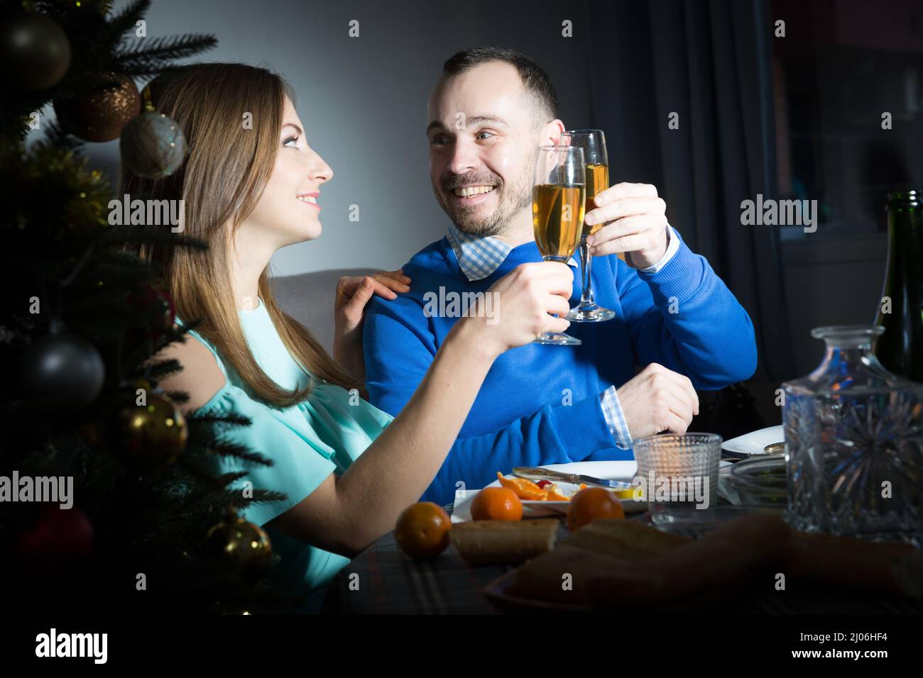 Couple souriant et aimant célébrant le nouvel an, donnant des toasts et appréciant le dîner à la maison Banque D'Images