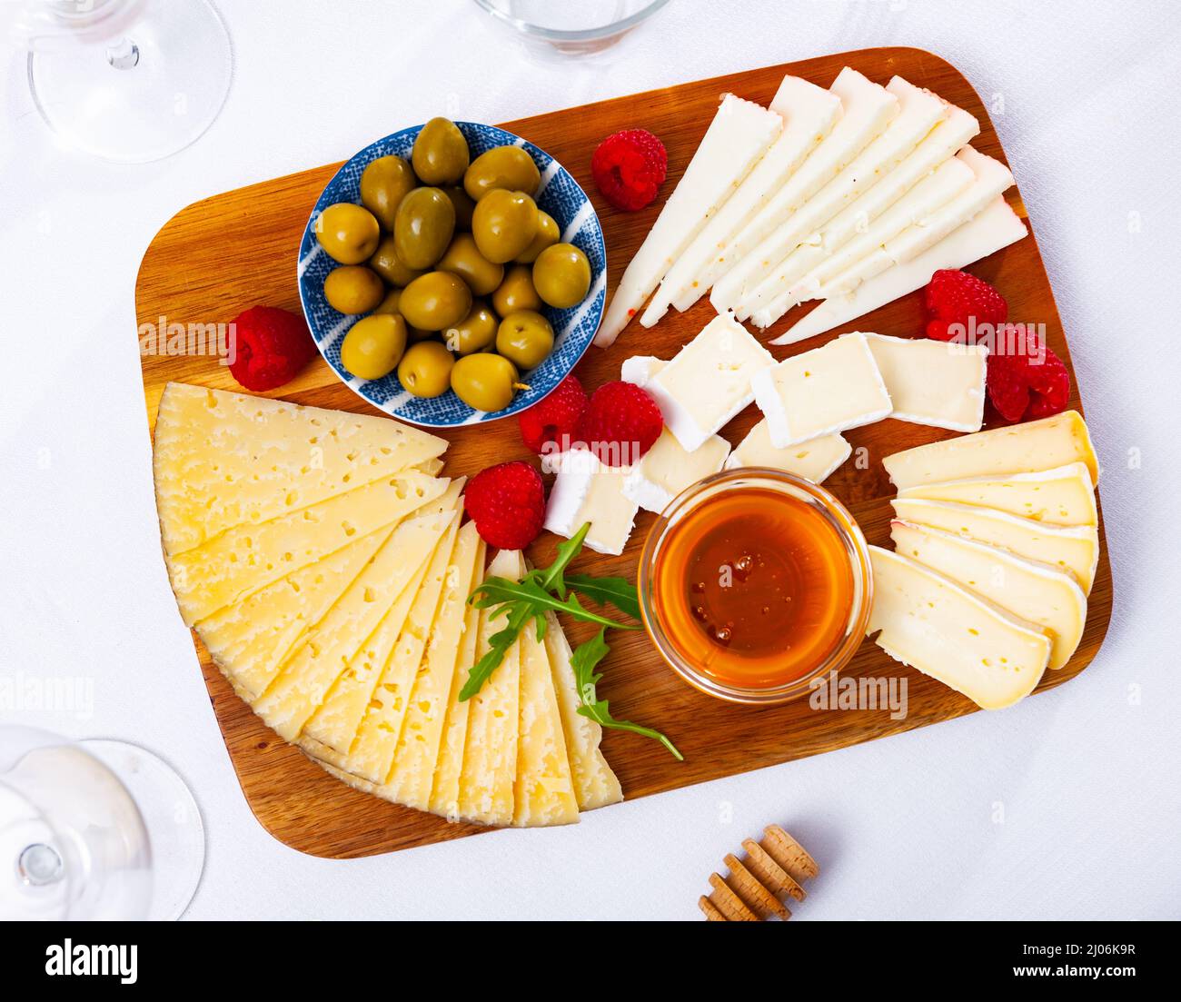 Assiette avec différents types de fromage, miel, framboises et olives Banque D'Images