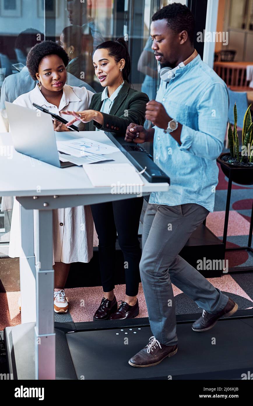 Faire couler tous leurs jus créatifs. Photo d'un homme d'affaires marchant sur un tapis roulant tout en ayant une réunion avec ses collègues dans un bureau. Banque D'Images